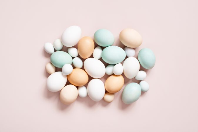 Top view of different colored eggs on pink background