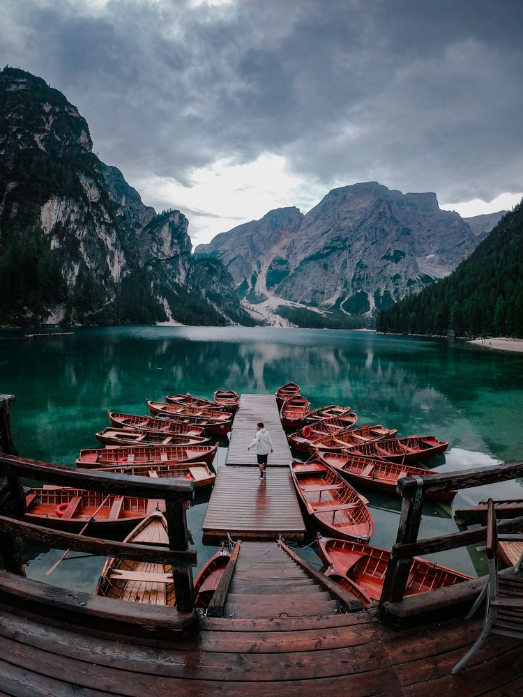 Man standing on a dock on a lake in Tirol, Trentino-South Tyrol, Italy
