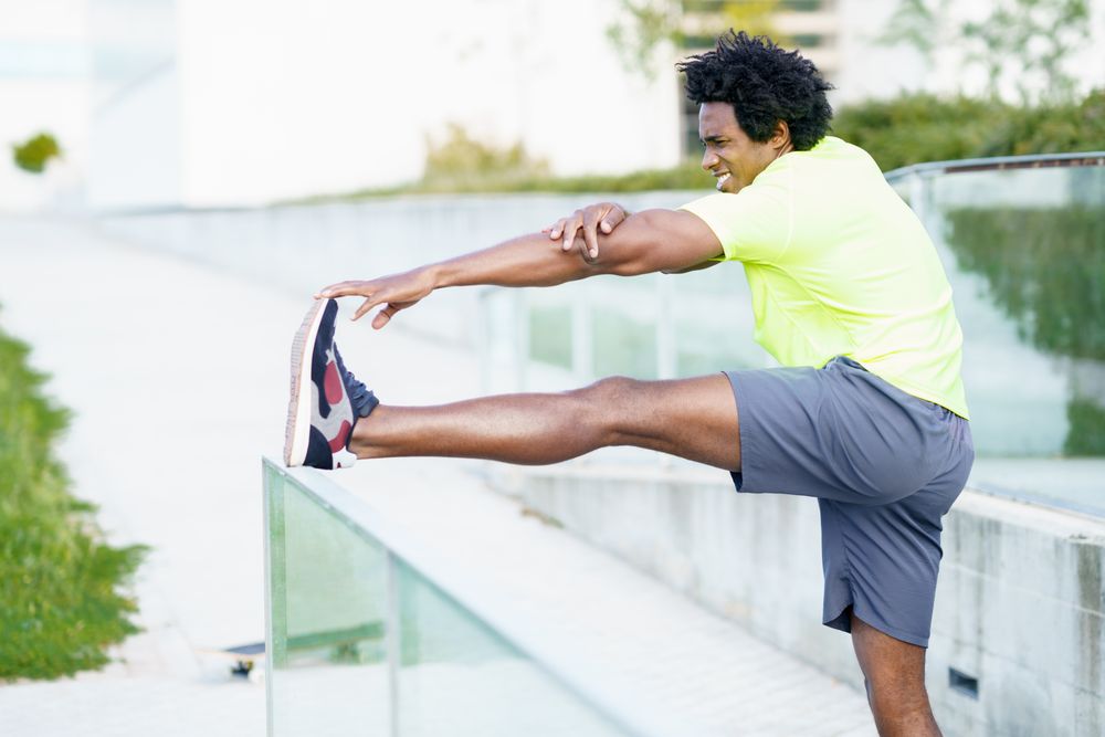 Male stretching his leg on outdoor railing
