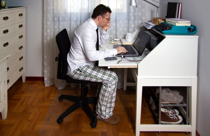 Man teleworking wearing shirt, tie and pajama pants