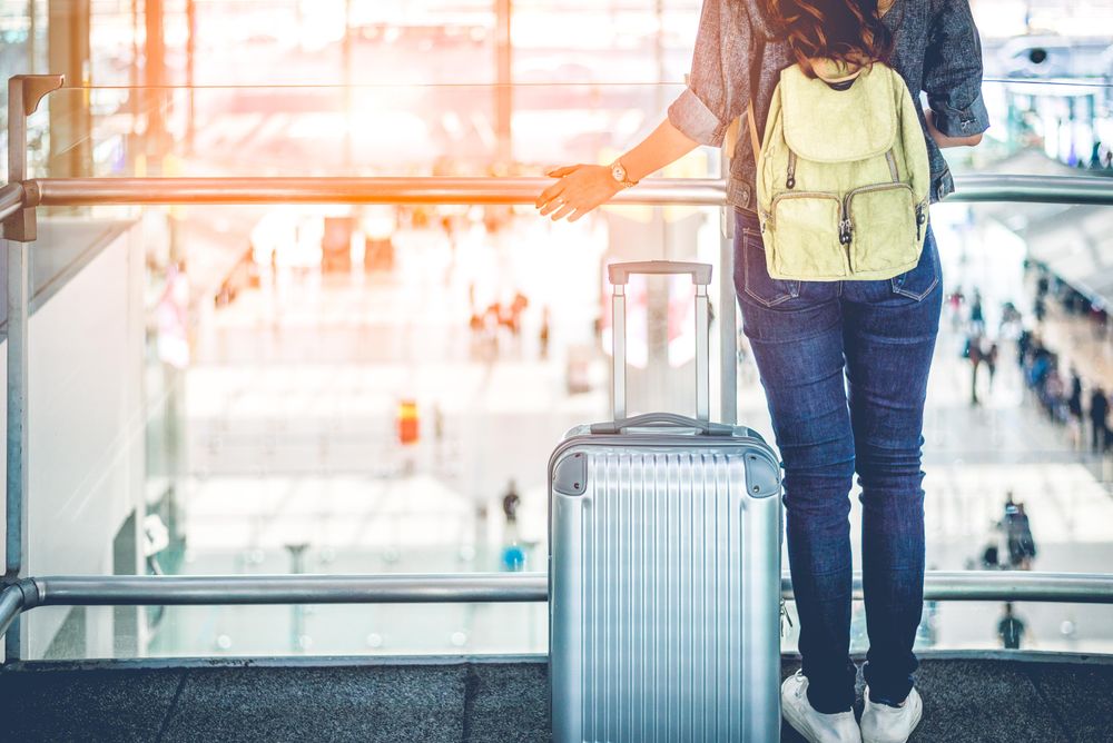Female traveler standing in bright airplane over looking passengers walking around