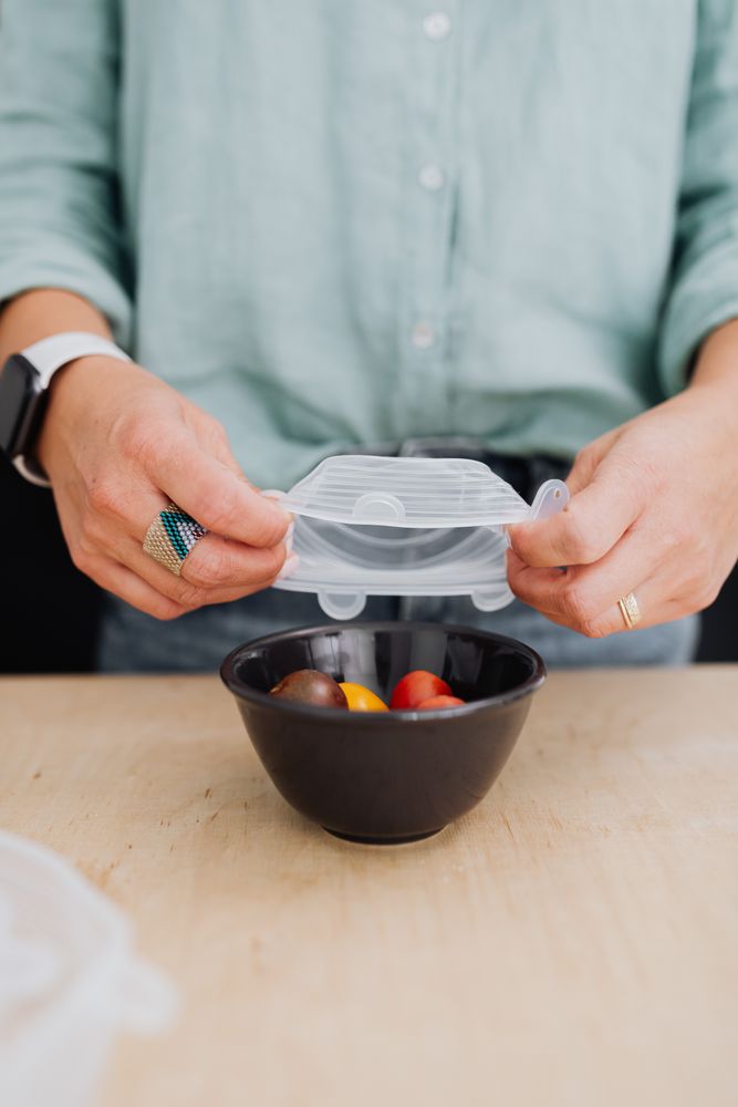 Cropped image of person covering a bowl of vegetables with plastic sealing