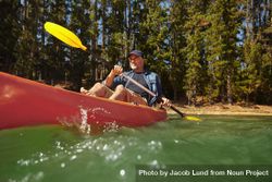 Portrait of mature man paddling a kayak in a lake 0WXEW5