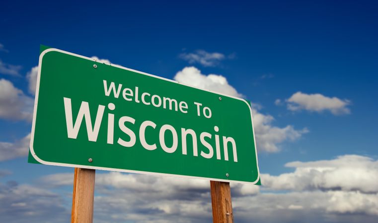 Welcome To Wisconsin Green Road Sign Over Blue Sky with Some Clouds.