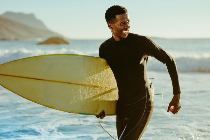 Happy young man with surfboard on beach