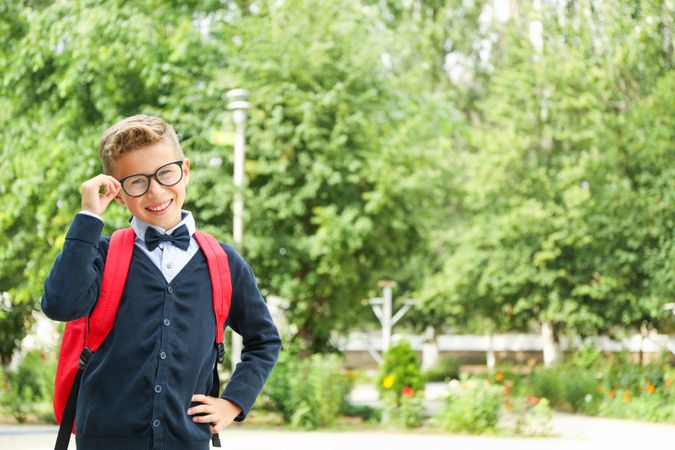 Boy in school uniform against greenery background, space for text