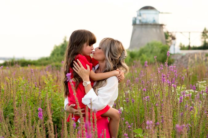 Mom and little daughter walking among meadow flowers