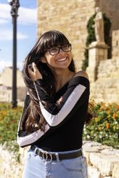 Portrait of young woman smiling while playing with her hair in the street