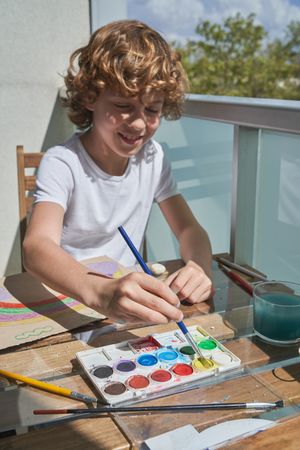 Smiling kid painting with watercolor paints