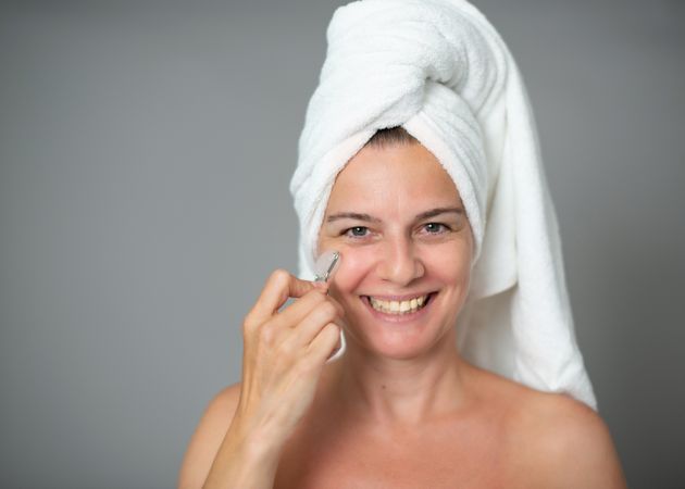 Cheerful female massaging face with jade roller