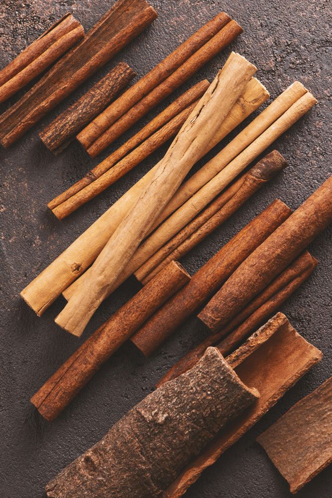 Different sizes of cinnamon sticks on brown background