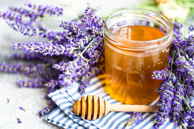 Close up of pot of honey surrounded by lavender
