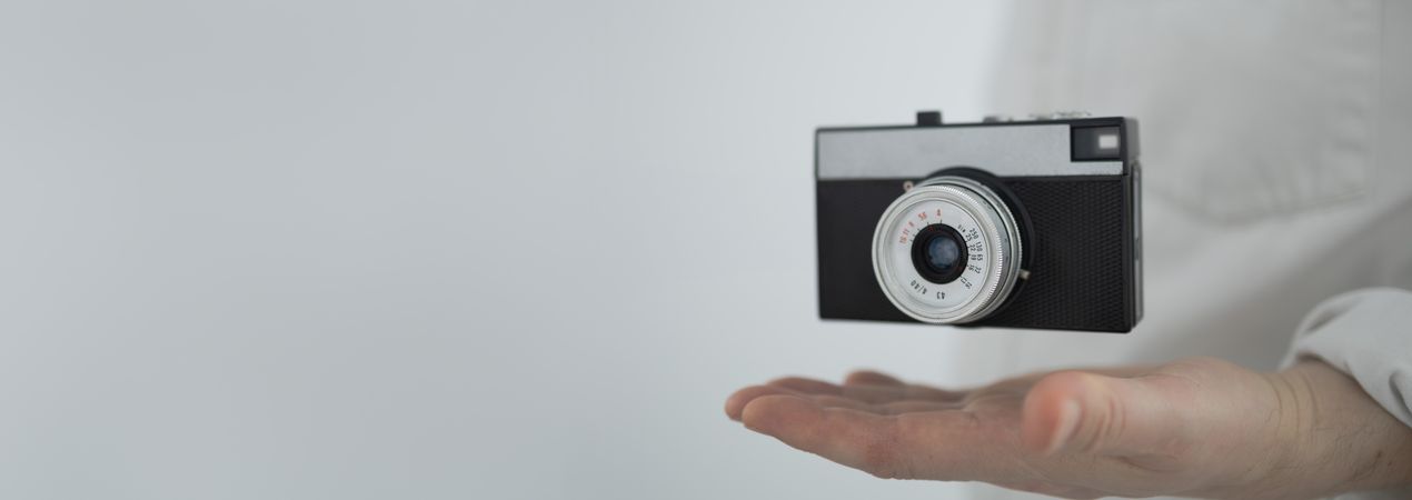 Floating retro camera above hand banner