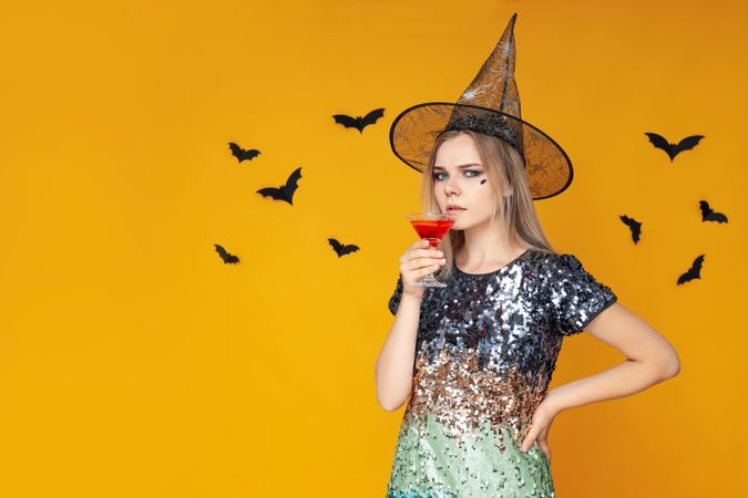 Concept of Halloween, young woman on yellow background