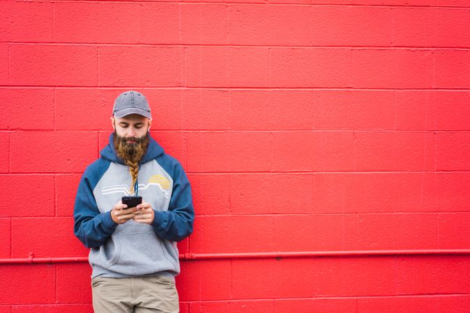 Man using smartphone near red wall