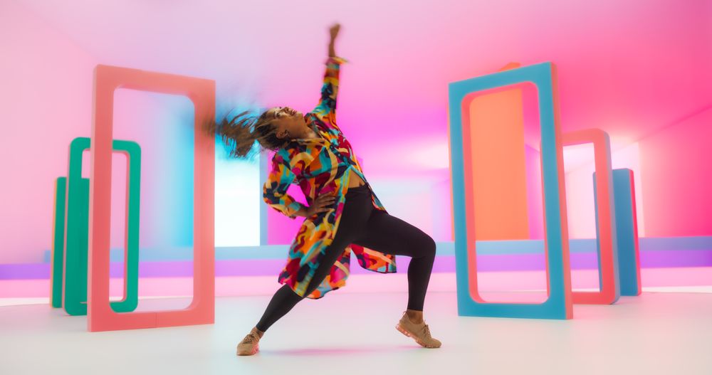 Colorful Geometric Abstract Aesthetic: Portrait of Black Woman Happily Dancing to Energetic Music in a Studio.