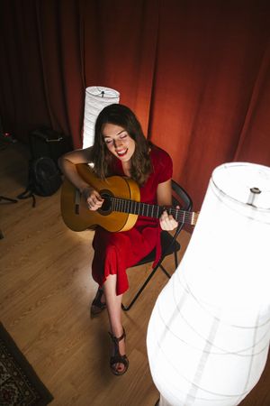Woman singing and playing guitar on stage in lamplight