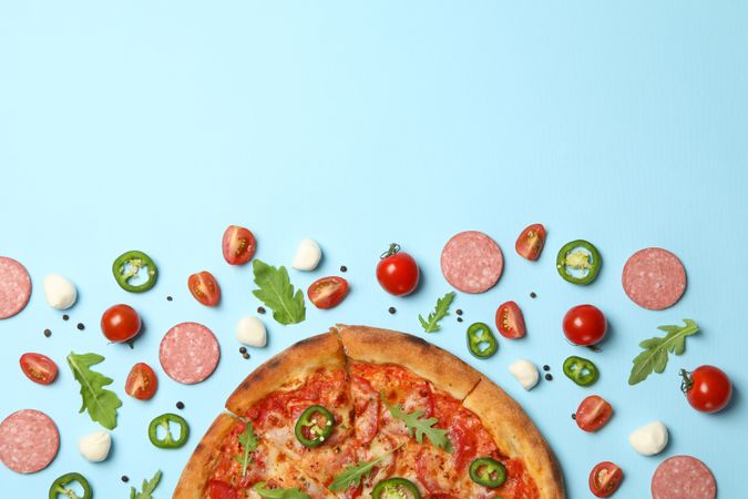 Tasty pizza and ingredients on blue background