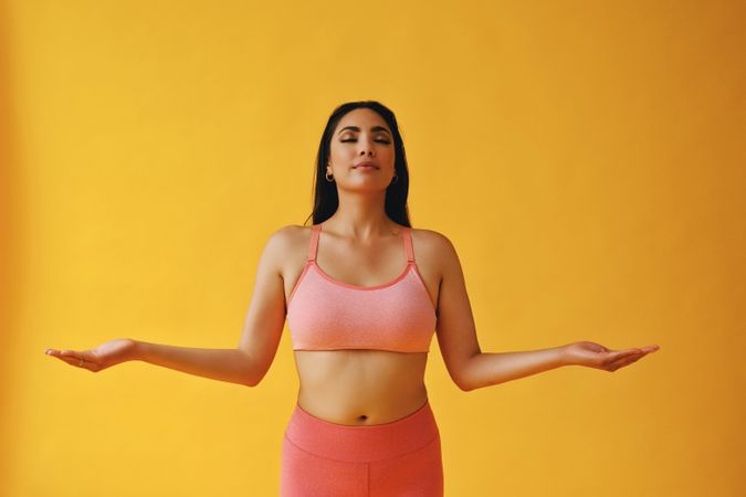 Hispanic female in yoga clothes with arms out in pose, copy space