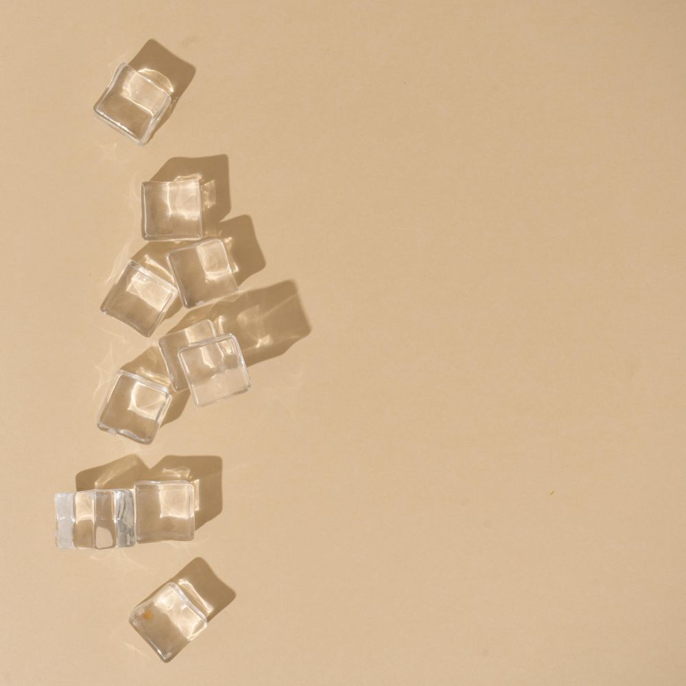 Flat lay of ice cubes on beige background with shadows