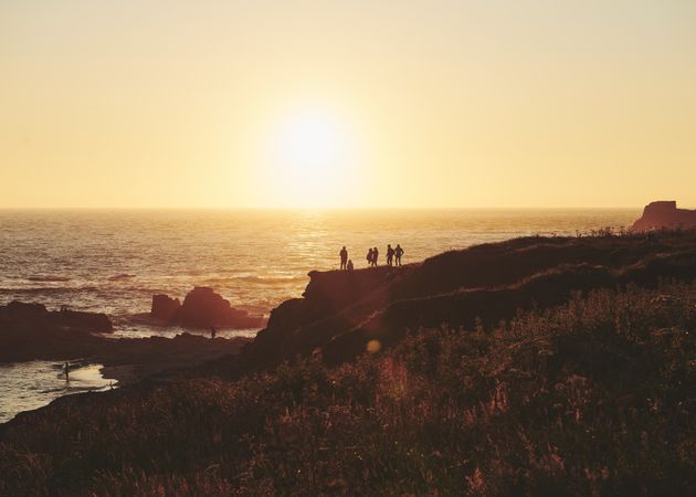 People on a cliff watching a beautiful sunset over the sea