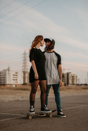 Man helping girlfriend to skate on road