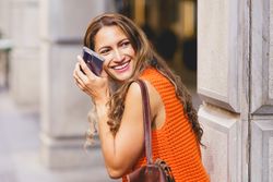 Smiling woman looking around holding phone