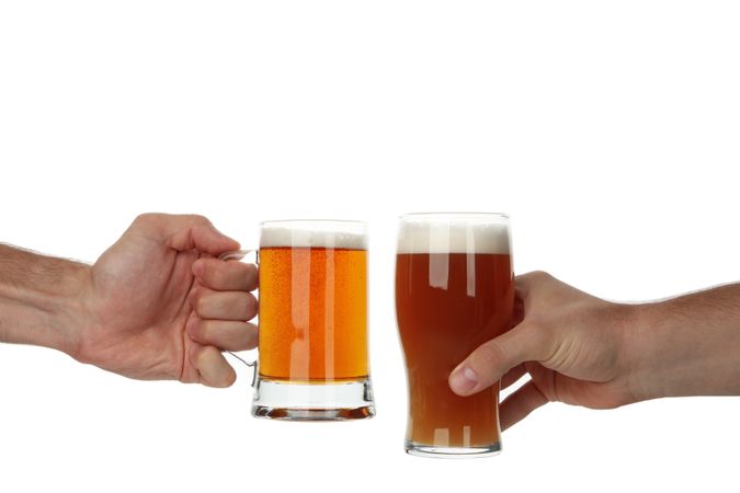 Hands hold glass of beer, isolated on light background