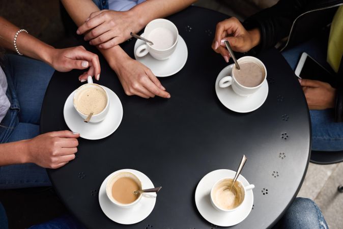 Shot of table of cappuccinos & lattes with hands