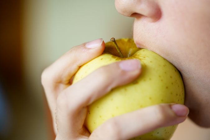 Side view of girl biting into apple