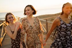 Three laughing woman walking on coastal pedestrian walkway