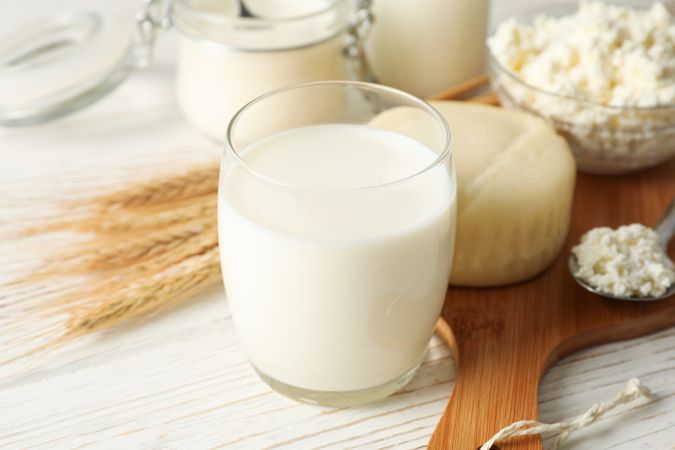Spikelets of wheat, dairy products and board on wood background, closeup