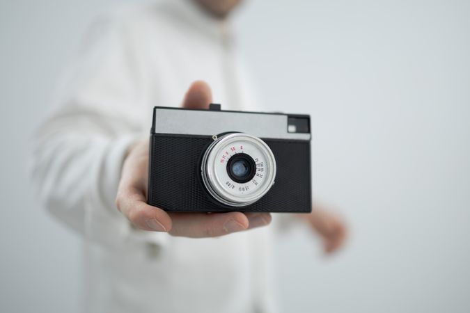 Man holding retro camera on light background