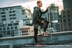 Athlete standing near a rooftop staircase with a medicine ball in hand 4BokPb