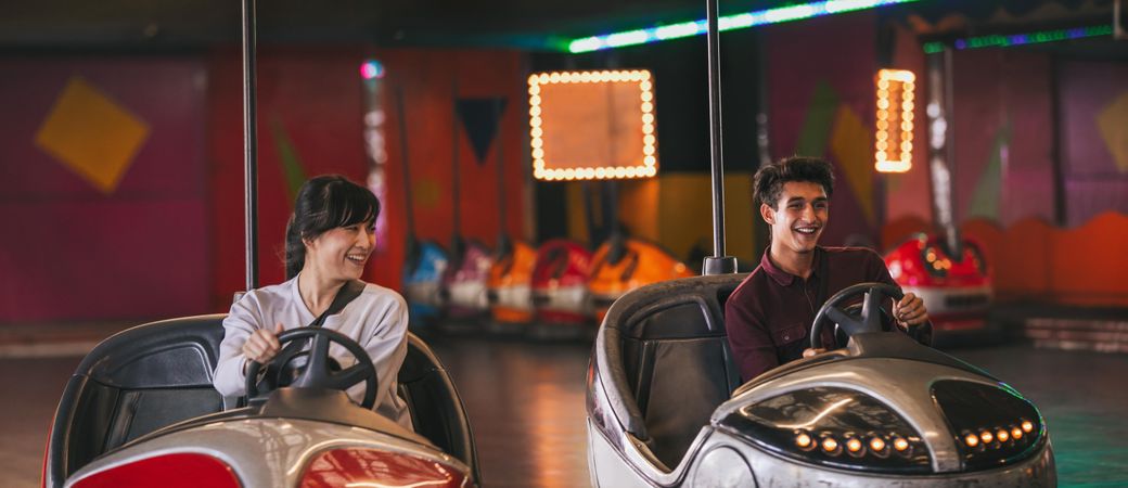 Happy young man and woman driving bumper cars