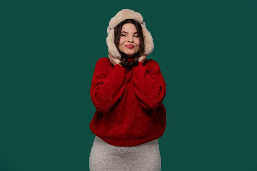 Happy woman in red sweater holding fur hat