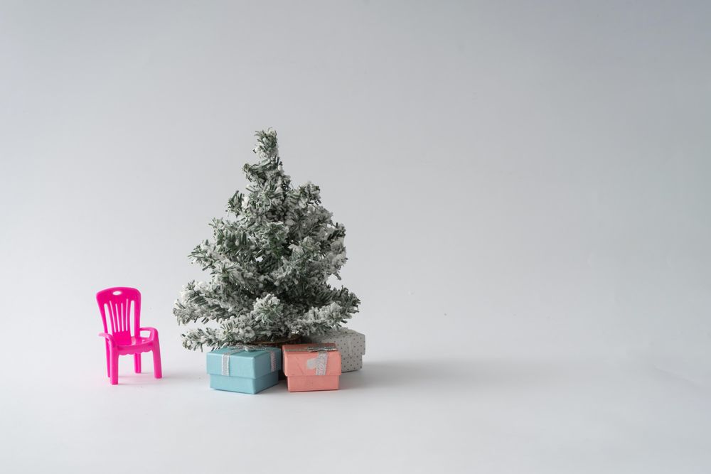 Snowy Christmas tree with presents underneath and pink chair