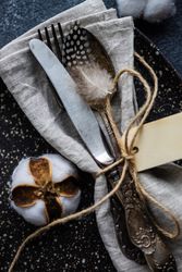 Top view of table setting on concrete background with decorative cotton and feathers with napkin on plate
