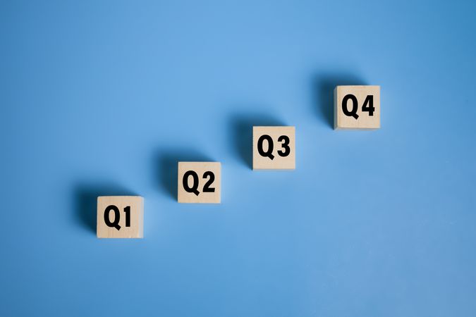 wooden cubes with q1, q2, q3, q4 symbol isolated on blue background. concept of quarterly report annual