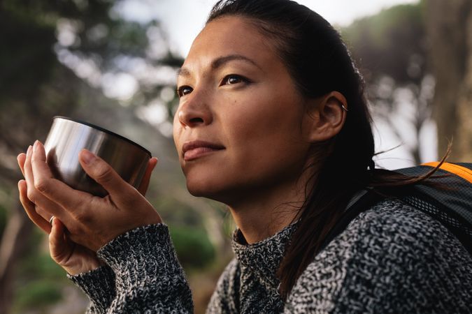 Asian woman having coffee outside on trail