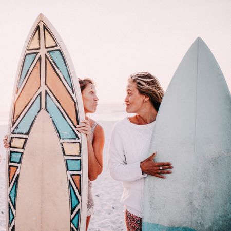 Two young women holding surf boards at the beach