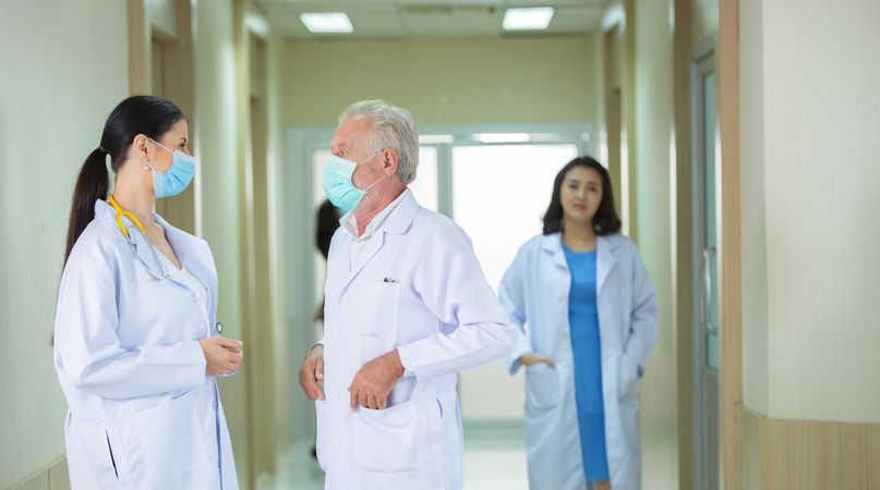 Mature male doctor and female doctor having a discussion in the hospital hallway