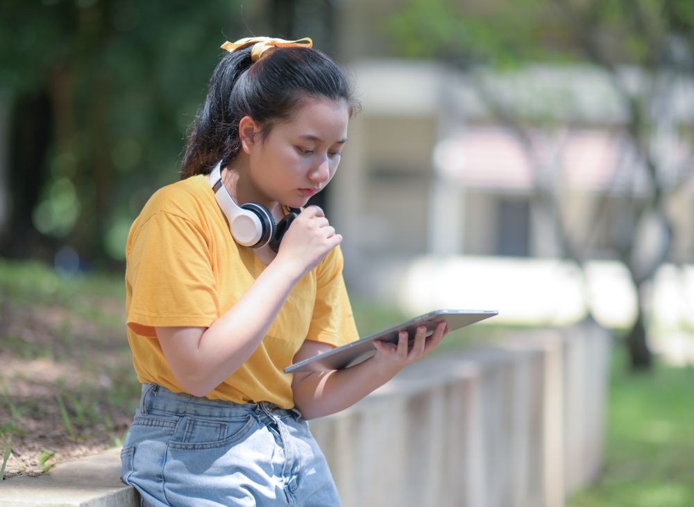 A woman looks down at the tablet in her hand with a worried expression.
