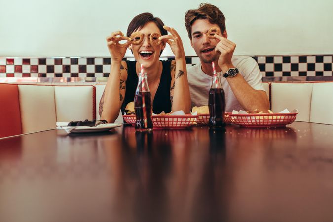 Smiling man and woman at a diner sitting with food and soft drinks on the table