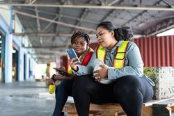 Women in high visibility vests sitting outside of work and taking a break