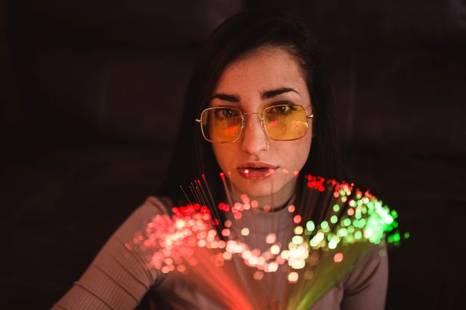 Young woman with fairy lights in darkness