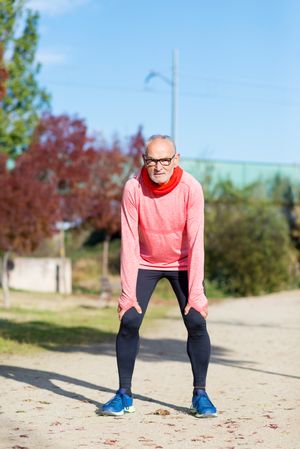 Grey haired man in red shirt and glasses resting between exercising