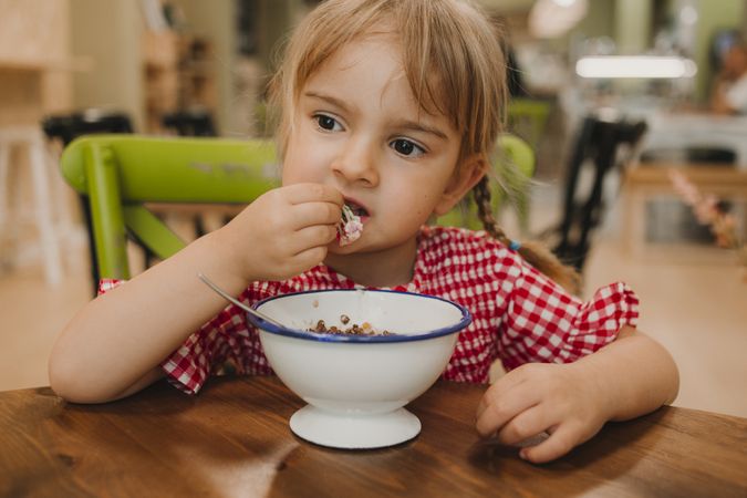 Girl eating with hand from white bowl