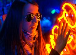 Stylish young woman near illuminated board