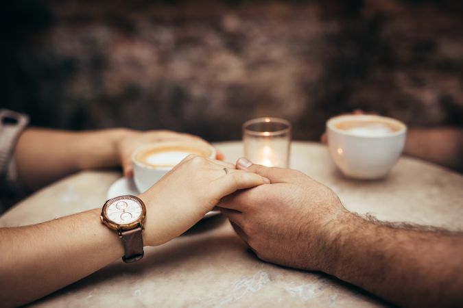 Close up of hands of a couple in love at a coffee shop